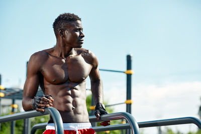 Low angle view of young man exercising against sky