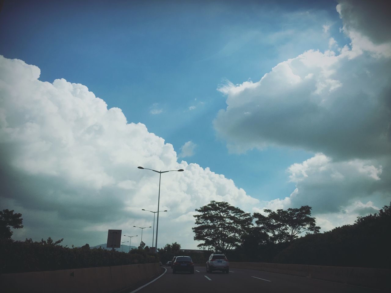 transportation, sky, car, road, land vehicle, cloud - sky, mode of transport, cloudy, street, the way forward, street light, cloud, tree, silhouette, road marking, on the move, electricity pylon, diminishing perspective, outdoors, nature