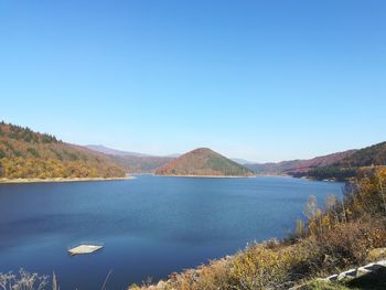 Scenic view of lake and mountains against clear blue sky