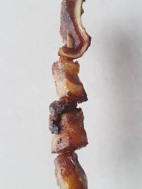 Close-up of meat on barbecue against white background
