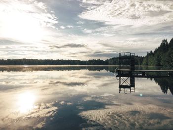 Pier reflecting on calm lake against sky