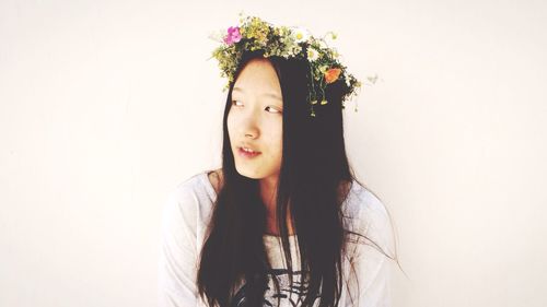 Young woman wearing flowers against white background