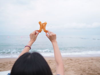 Midsection of woman on beach against sky