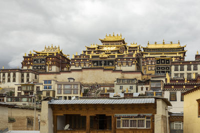 Low angle view of buildings against cloudy sky