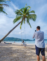 Rear view of woman standing at beach against sky