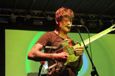 Low angle view of mature musician playing guitar at stage in nightclub