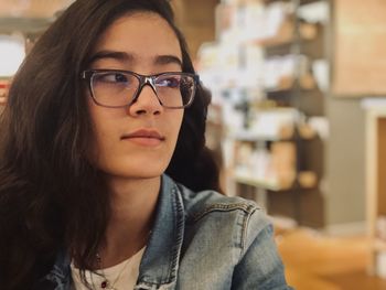 Close-up of young woman looking away while sitting at home