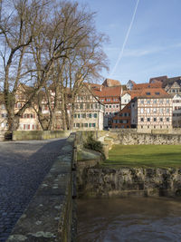 Houses by river and buildings against sky