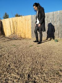 Full length of young man standing on field against sky