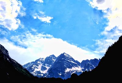 Low angle view of snowcapped mountain against cloudy sky