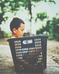 Side view of boy sitting on bucket