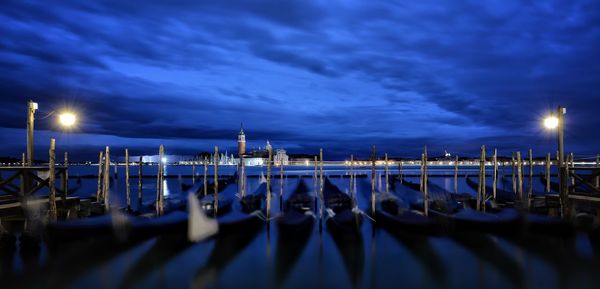 Boats moored at harbor against blue sky