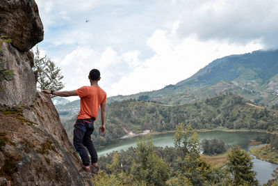 Full length of male rock climber looking at mountain against sky