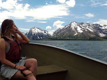 Woman looking at snowcapped mountains while traveling on boat at sea