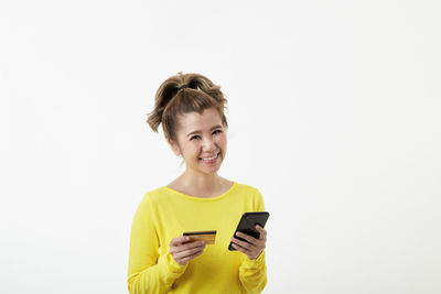 Smiling young woman using smart phone against white background
