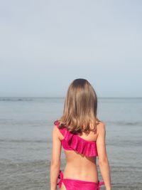 Rear view of woman standing in sea against sky