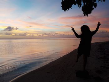 Silhouette woman standing on beach against sky during sunset