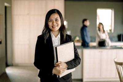 Portrait of saleswoman with folder standing at new home