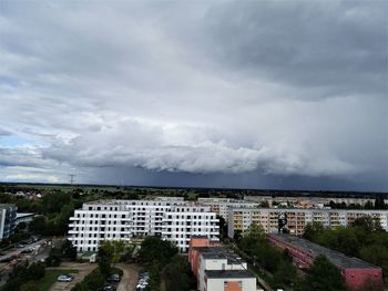 High angle view of buildings in city against storm clouds