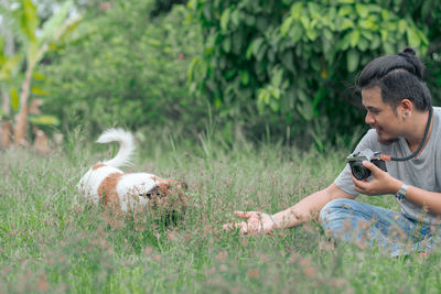 Smiling photographer with dog on grassy land