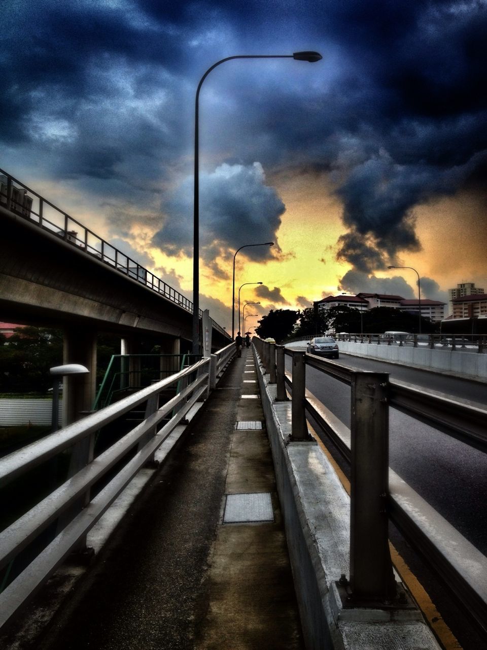 sky, cloud - sky, built structure, architecture, cloudy, transportation, railing, the way forward, connection, bridge - man made structure, street light, cloud, sunset, diminishing perspective, railroad track, rail transportation, weather, overcast, dramatic sky, dusk