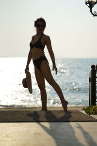 Full length portrait of woman in bikini standing at beach