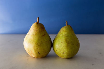 Close-up of pears on table against blue wall