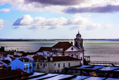 Buildings by sea against sky