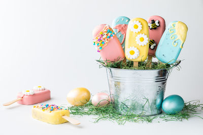 Easter themed cakesicles in a tin pail against a light background.