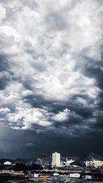 Buildings in city against storm clouds