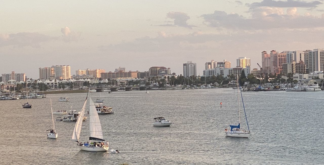 SAILBOATS ON SEA BY BUILDINGS AGAINST SKY