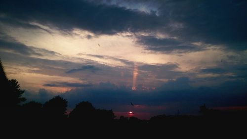 Silhouette of trees against cloudy sky