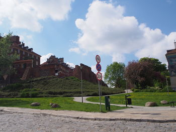 Road by trees and buildings against sky