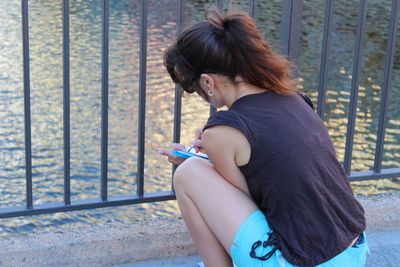 Side view of young woman standing on railing