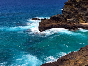 Rock formation in sea against clear blue sky