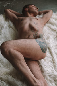 Midsection of shirtless man lying on bed