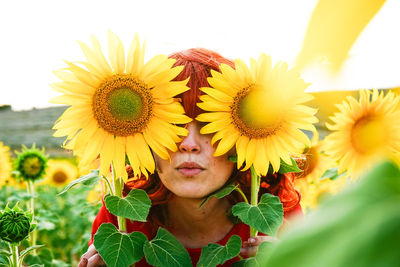 Smiling young woman with yellow flowers in field