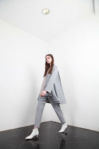 Young woman standing against white wall