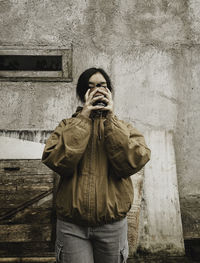 Young woman standing against wall