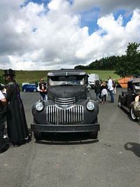 Cars on road against cloudy sky