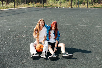 A couple of teenage girls on a sports street court with a basketball lifestyle relax after 