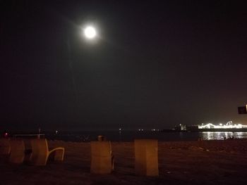 Illuminated beach against sky at night