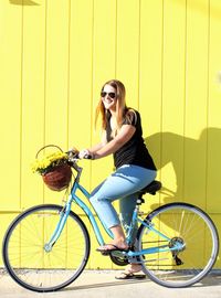 Young woman wearing sunglasses while sitting on bicycle