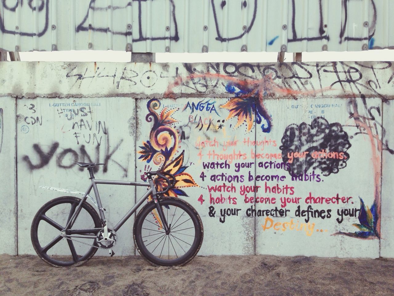 text, graffiti, bicycle, western script, wall - building feature, communication, art and craft, art, creativity, wall, street art, capital letter, built structure, day, architecture, transportation, no people, outdoors, non-western script, parking