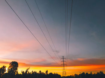 Silhouette electricity pylon against romantic sky at sunset