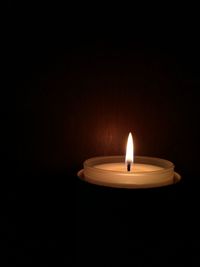 Close-up of lit candle against black background