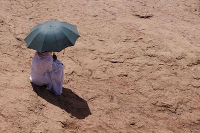 Rear view of person with umbrella sitting on land