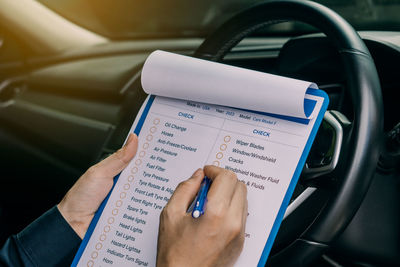 Cropped hands of man using mobile phone while sitting in car