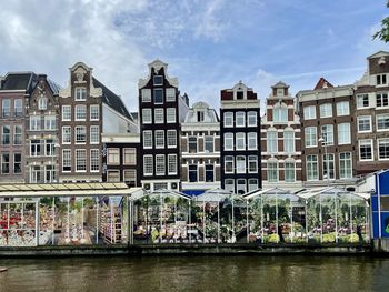 Buildings by river against sky