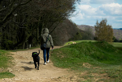 Person walking with black dog on footpath in forest